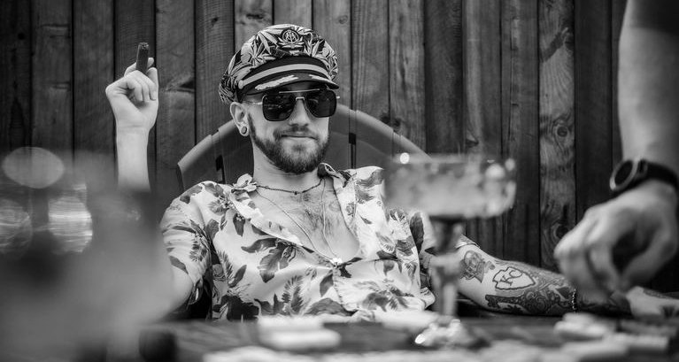 Alex Vincent in a captain's hat, seated in a patio chair